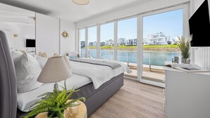 Een moderne slaapkamer met een bed, bedlampje en uitzicht op een waterlichaam.
