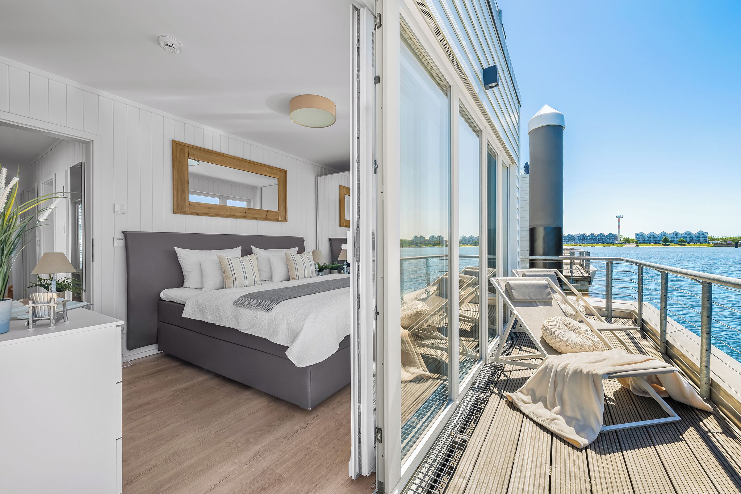 A modern bedroom with a bed, a desk, and a view of the water.