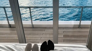 Een bed met uitzicht op zee door grote ramen.