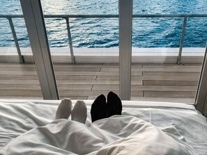 Ein Bett mit Blick auf das Meer durch große Fenster.
