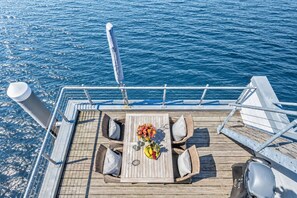 A deck with a table, chairs, and a railing overlooking the sea. - On Board 2 in the Baltic Sea resort of Olpenitz: Houseboat with a rooftop terrace and a view of the Schleif River (Olpenitz)