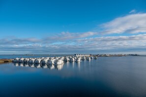 A waterfront property with multiple white buildings, calm water, and a clear sky. - On Board 2 in the Baltic Sea resort of Olpenitz: Houseboat with a rooftop terrace and a view of the Schleif River (Olpenitz)