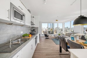 Eine moderne Küche mit integriertem Mikrowellenherd, einer Edelstahl-Spüle und einem Essbereich mit Tisch und Stühlen.