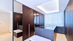 Une chambre à coucher moderne avec une table en verre, un lambris en bois foncé, un dressing et une lucarne.