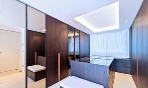 Ein modernes Schlafzimmer mit Glastisch, dunklen Holzvertäfelungen, begehbarem Kleiderschrank und einem Oberlicht.