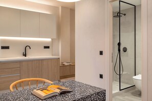 A modern bathroom with a glass-enclosed shower, a white sink, and a wooden chair with a book. - Helena’s Retreat: Relaxation and Greek hospitality (Ρόδος)