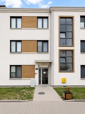 Ein mehrstöckiges Gebäude mit flacher Fassade, großen Fenstern und einem zentralen Eingang.