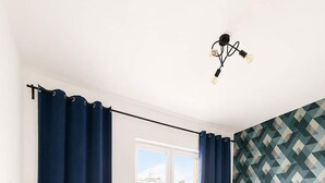 A bedroom with a bed, a desk, a chair, a window, and a wall with a geometric pattern.