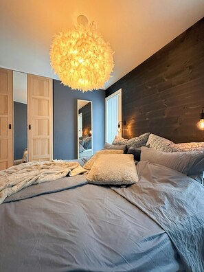 A bedroom with a large bed, a mirror, and a unique ceiling light fixture. - Architect drawn home with amazing view over Nisser (Treungen)