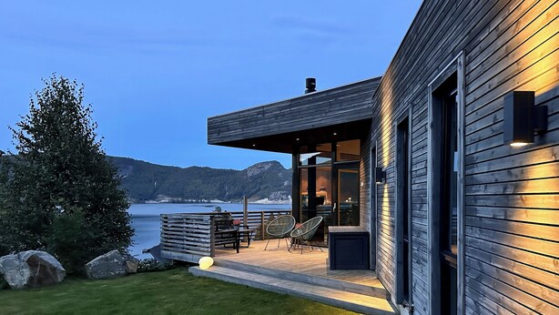 A modern house with a deck, outdoor seating, and a view of the water. - Architect drawn home with amazing view over Nisser (Treungen)