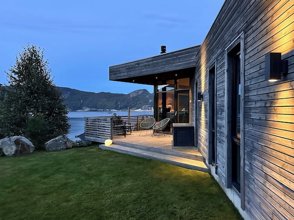 A modern house with a deck, outdoor seating, and a view of the water. - Architect drawn home with amazing view over Nisser (Treungen)