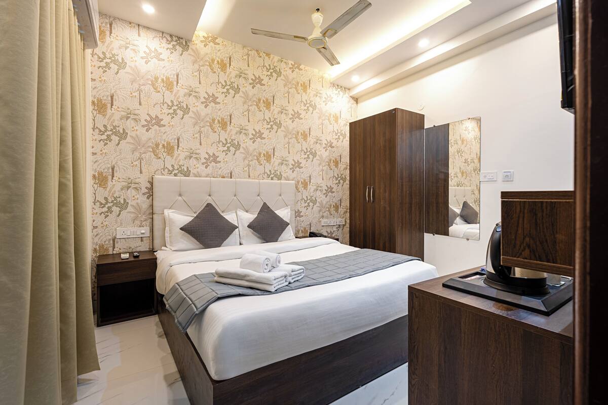 A hotel room with a bed, nightstand, wardrobe, and a mirror.