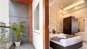 A balcony with a potted plant, a bed with a headboard, a wardrobe, and a mirror. - Rv Grand Varanasi (Varanasi)