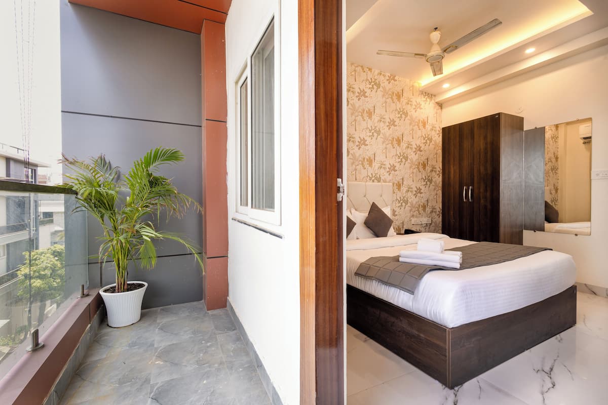A balcony with a potted plant, a bed with a headboard, a wardrobe, and a mirror.