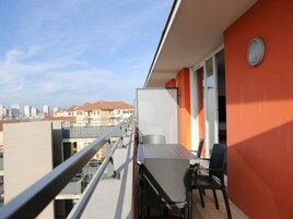 A balcony with a table and chairs, a city view, and a red wall.
