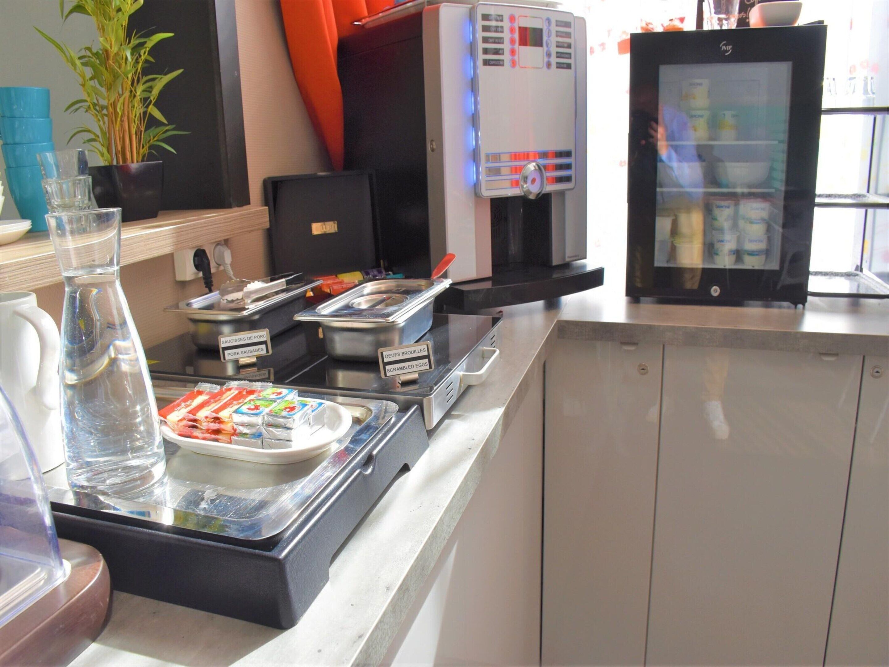 Un área de bufé con opciones de comida identificadas, un dispensador de agua y un refrigerador.