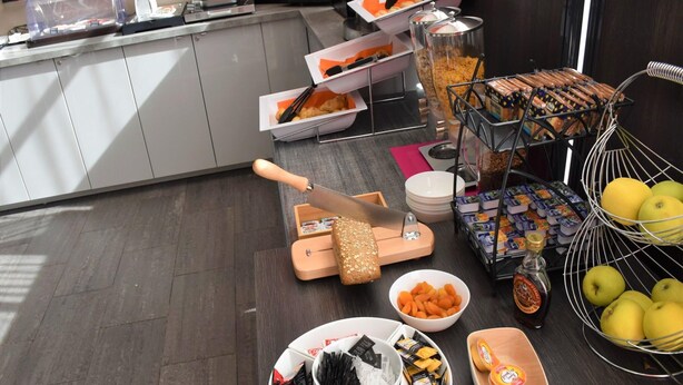 Montaje de bufé con diversos alimentos, un cuchillo y una cesta de frutas.
