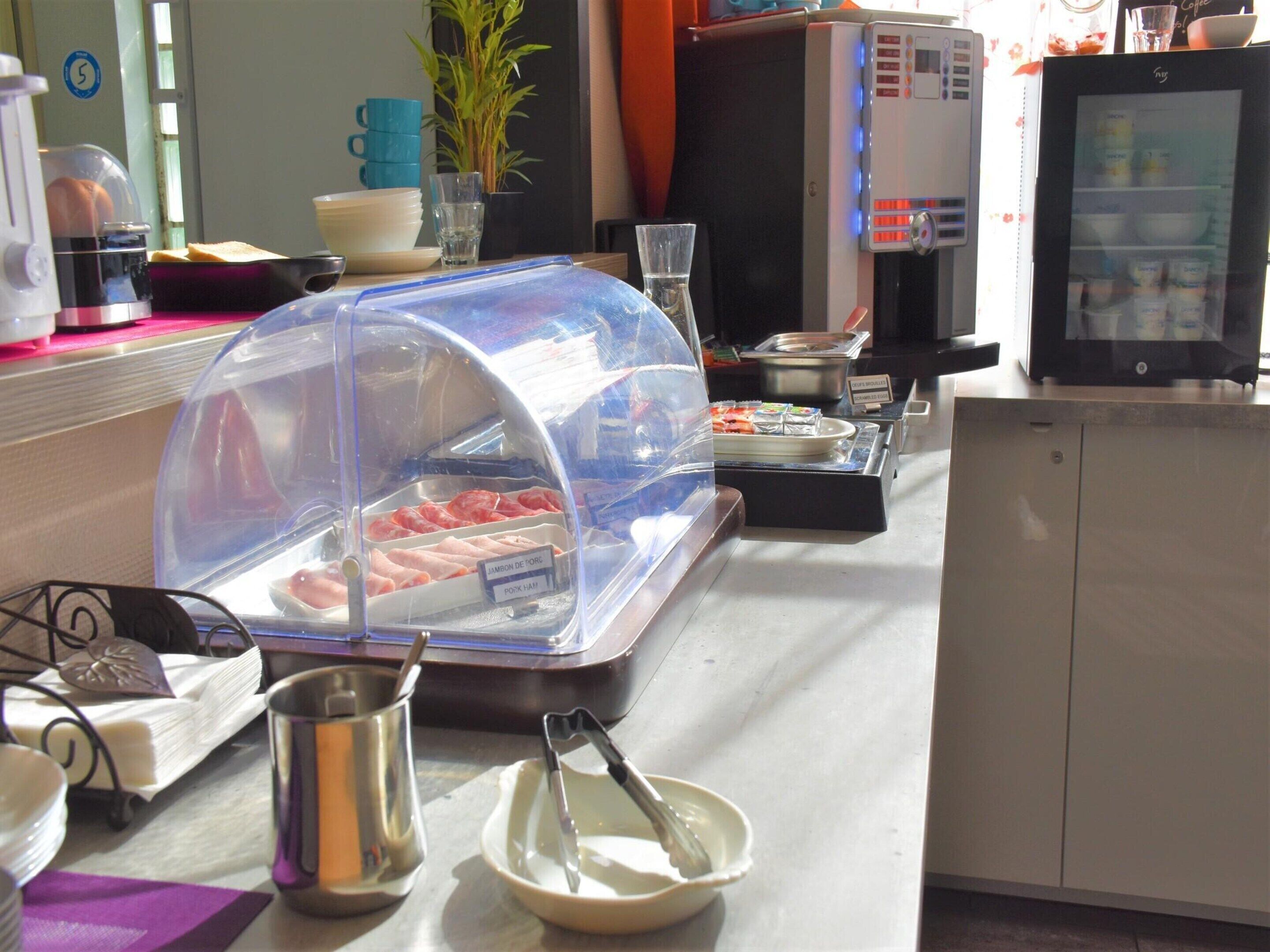 A buffet setup with a covered food display, a coffee machine, and a refrigerator.