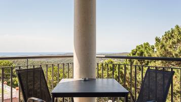 A balcony with a table and chairs, overlooking a mountainous landscape.