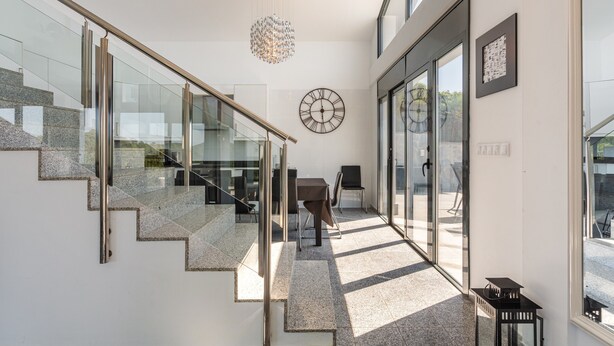 Een modern interieur met een trap, een kroonluchter en een wandklok.