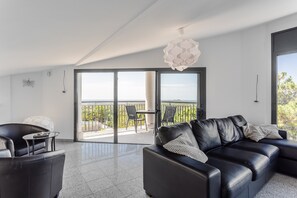 Ein modernes Wohnzimmer mit einem schwarzen Ledersofa, einem Glastisch und einem Balkon mit Blick.