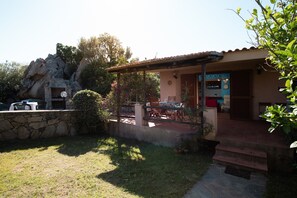 Ein Haus mit Terrasse, Steinmauer und kleinem Garten.
