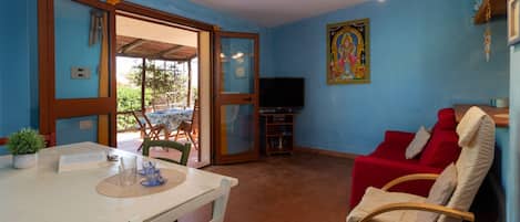 Una habitación con una mesa de comedor, un sofá rojo y una televisión.