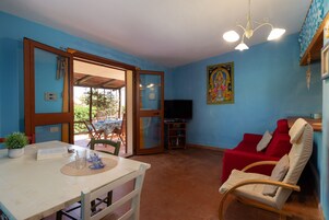 Una habitación con una mesa de comedor, un sofá rojo y una televisión.