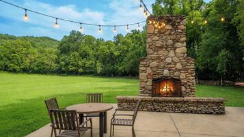 An outdoor patio with a stone fireplace, a round table, and two chairs.