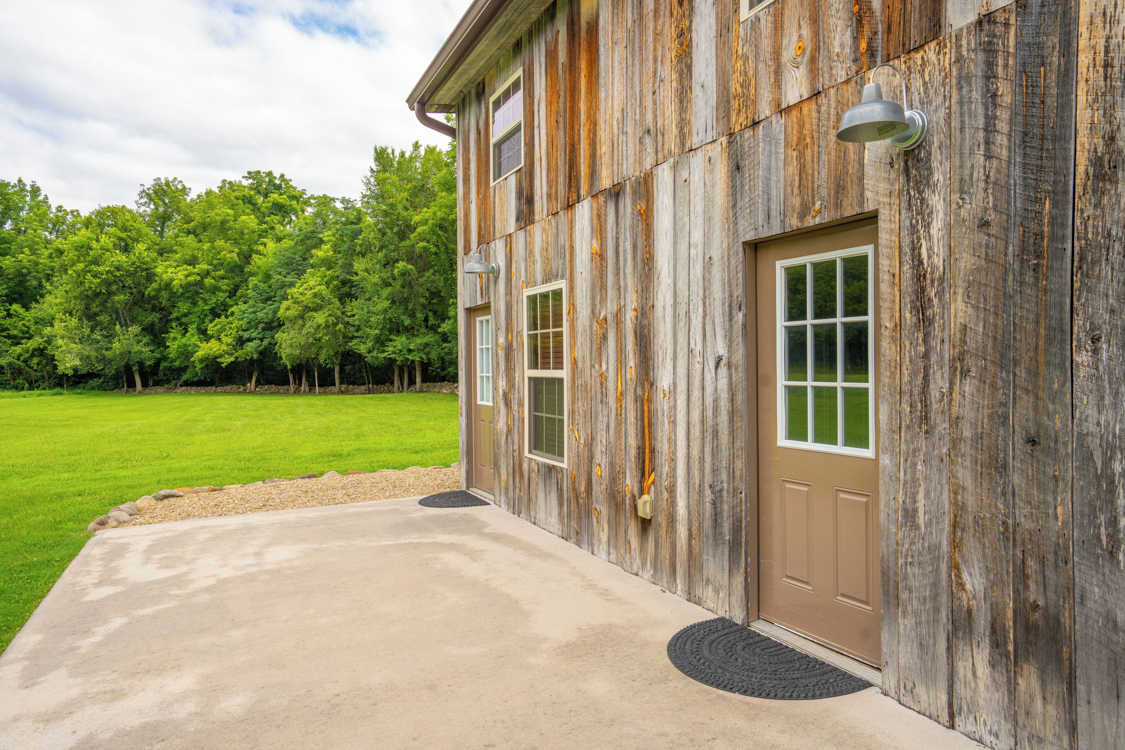 A rustic building with a concrete driveway and a wooden door.
