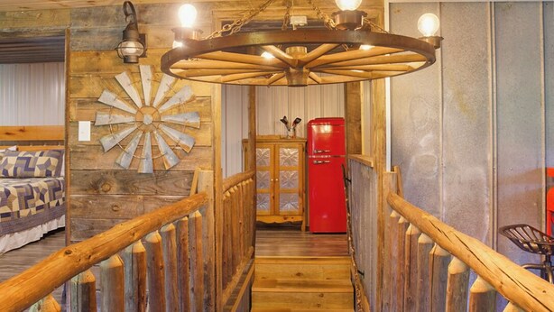 Un intérieur en bois avec un escalier en colimaçon, un réfrigérateur rouge et un lit avec une literie à motifs.