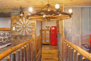 A wooden interior with a spiral staircase, a red refrigerator, and a bed with patterned bedding. - TBarnLoft@FF: Honeymoon, Outdoor Fireplace, Wifi, Water View, Large Yard (Cosby)
