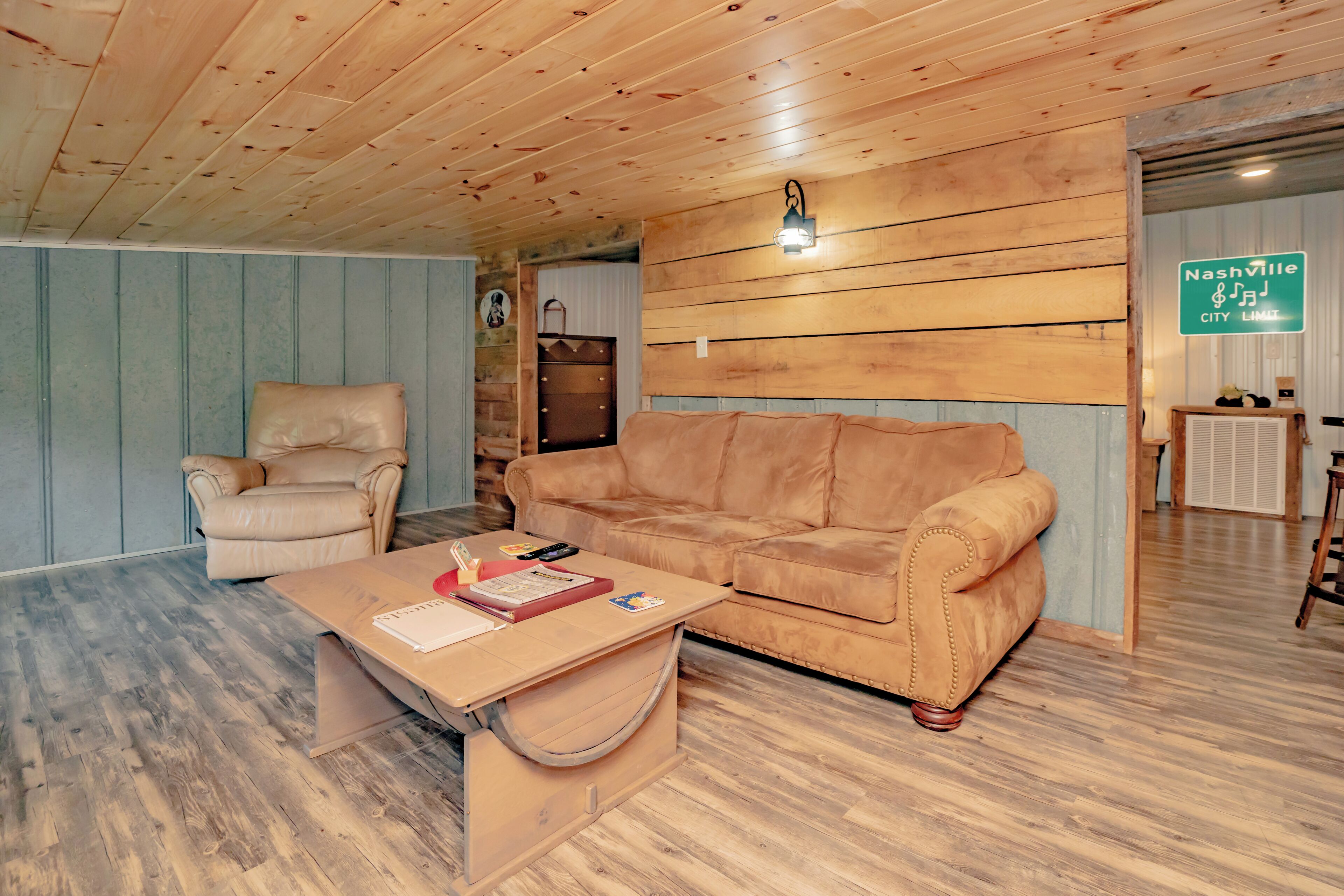 A cozy room with a wooden ceiling, a leather sofa, a wooden coffee table, and a chair.
