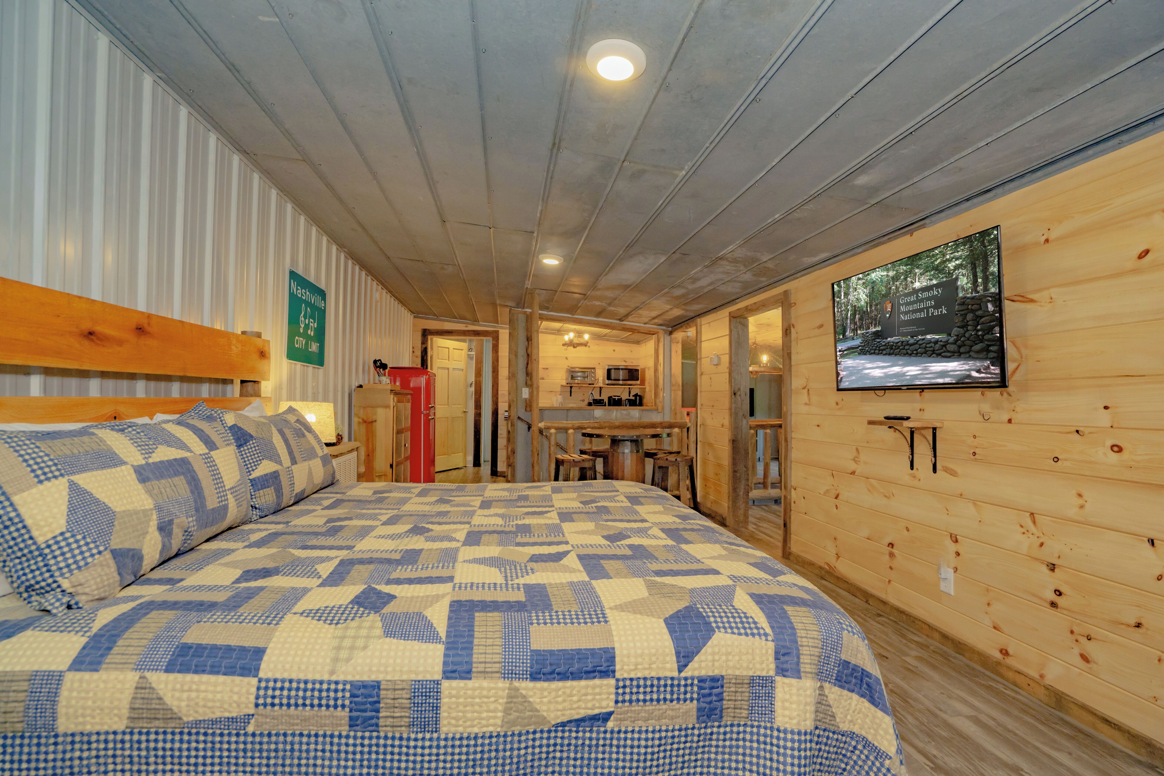 Ein Zimmer mit einem Bett, einer Holzwand, einer Küchenzeile und einem Schild, das die Stadtgrenze kennzeichnet.