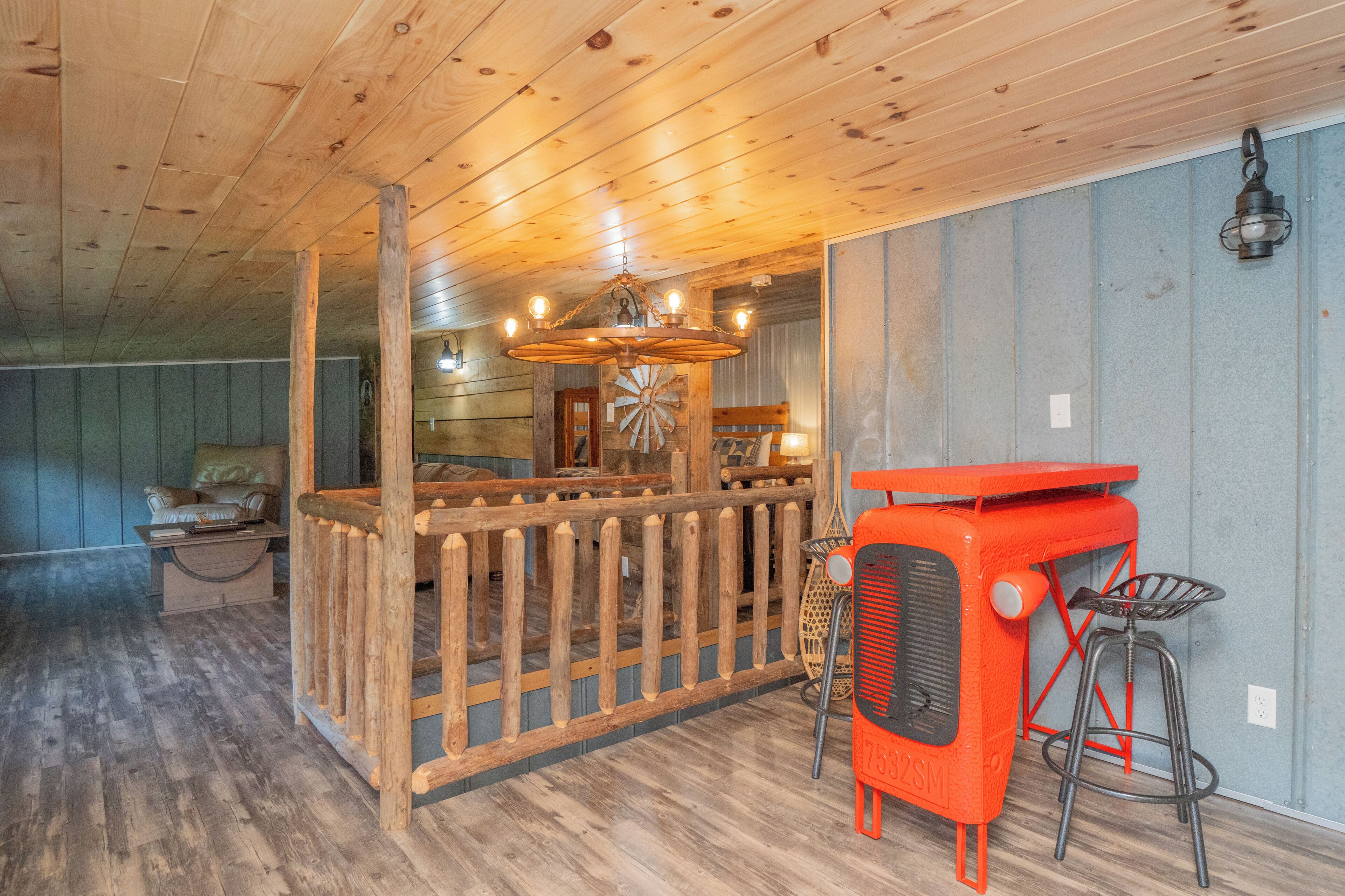 A rustic interior with a wooden ceiling, a wooden fence, a vintage radio, and a bar area with stools.