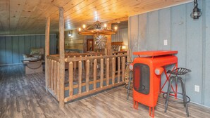 A rustic interior with a wooden ceiling, a wooden fence, a vintage radio, and a bar area with stools.