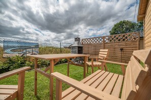 A wooden deck with a table and chairs, a metal grill, and a wooden fence. - Summer House in Dabrowa Near the Sea (Swierzno)