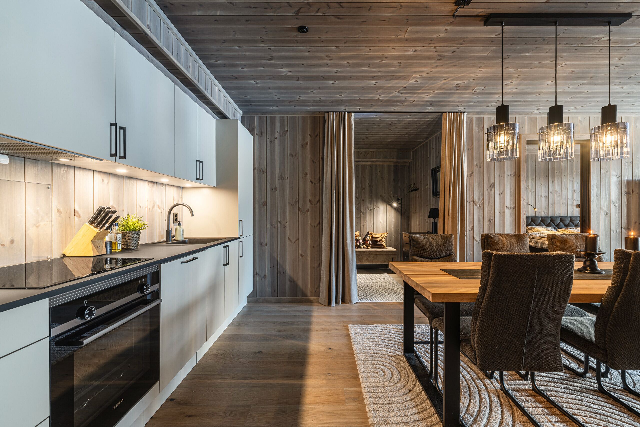 Una cucina moderna con elettrodomestici integrati, una zona pranzo con tavolo e sedie in legno, e un angolo soggiorno accogliente con divano e camino.