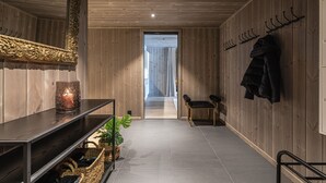 Ein Holzinnenraum mit Spiegel, Kerze, Bank und Garderobe.