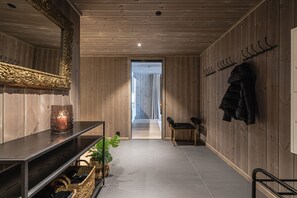 Un intérieur en bois agrémenté d’un miroir, d’une bougie, d’un banc et d’un porte-manteau.