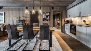 Eine moderne Küche mit Holzschränken, ein Essbereich mit Holztisch und -stühlen sowie Pendelleuchten.