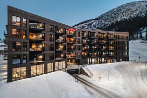 Ein mehrstöckiges Hotel mit Balkonen, großen Fenstern und einem Schild, das auf einen Skiort hinweist.