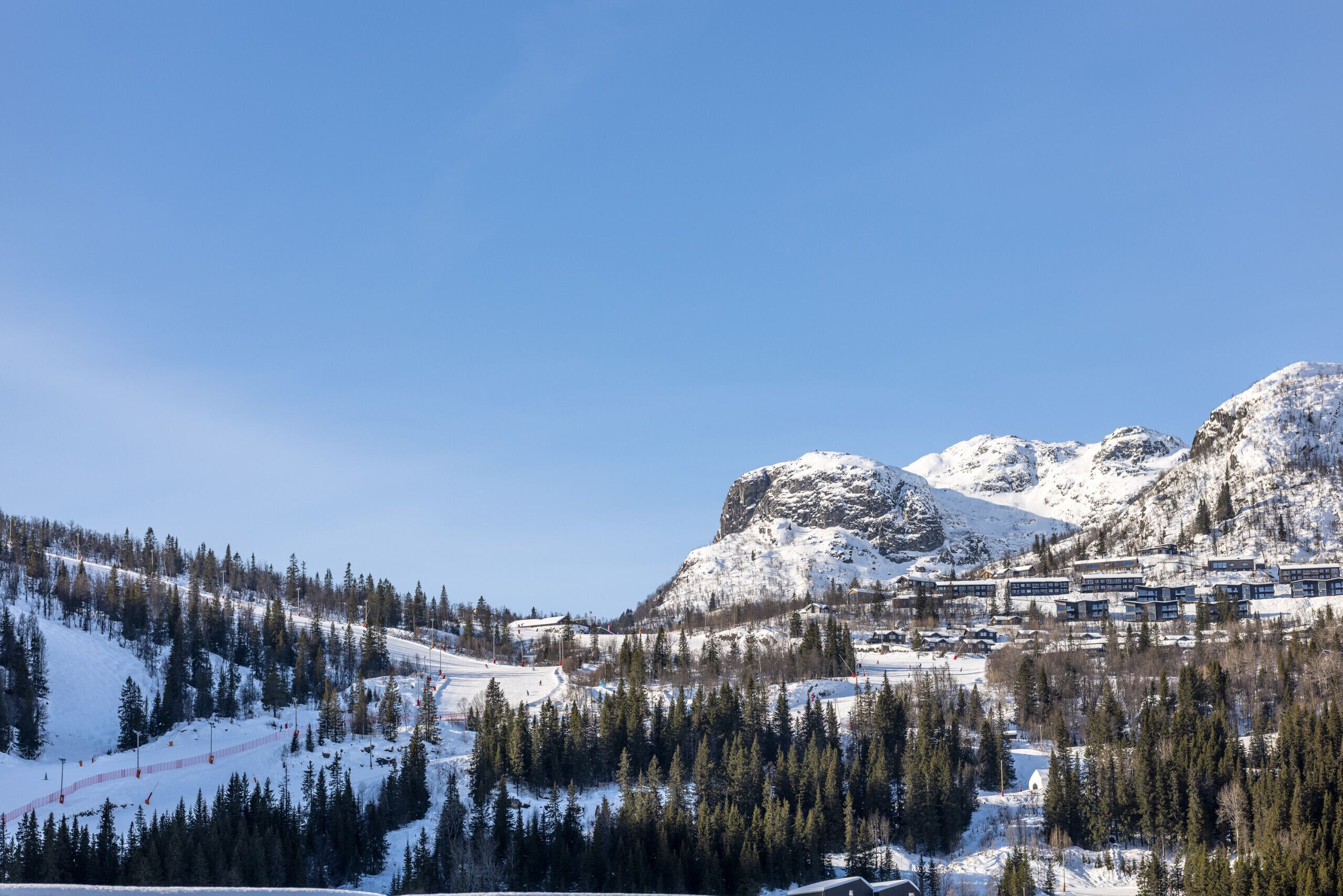 A snow-covered mountain landscape with a ski resort and buildings.