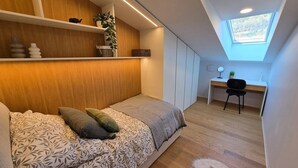Une chambre à coucher avec un lit, un bureau, une chaise et une lucarne.