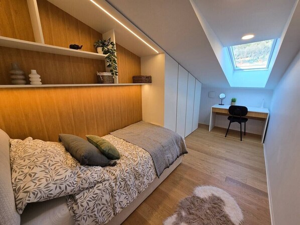 Une chambre à coucher avec un lit, un bureau, une chaise et une lucarne.