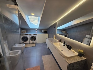 Un bany modern amb una finestra de sostre, un lavabo gran i una rentadora.
