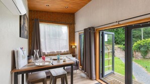 A dining area with a table, chairs, and a view of the outdoors. - Le Petit Haras De Valmont Chalet with Private Terrace, Garden, and Air Conditioning (Valmont)