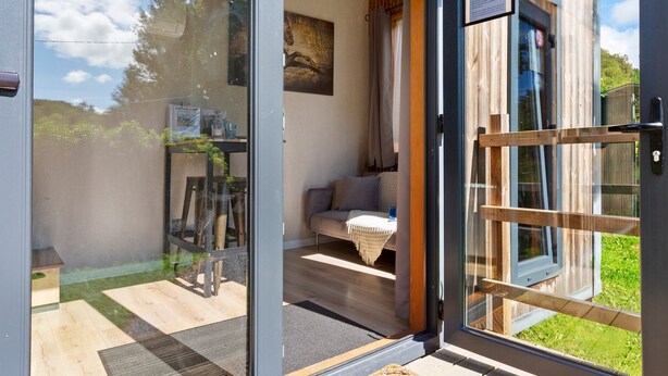 A modern, open-plan living area with a sofa, a small table, and a painting on the wall. - Le Petit Haras De Valmont Chalet with Private Terrace, Garden, and Air Conditioning (Valmont)