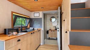 A compact kitchen with wooden cabinets, a window with a view, and a sink. - Le Petit Haras De Valmont Chalet with Private Terrace, Garden, and Air Conditioning (Valmont)