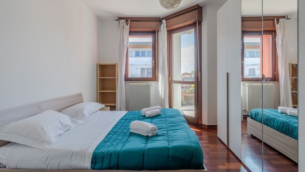 Ein Schlafzimmer mit einem Bett, einem Fenster, einem Spiegel und einer Heizung.